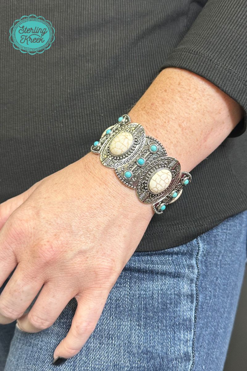 This one-of-a-kind silver bracelet is a real gem! Featuring unique turquoise and white stones, it's sure to add a sparkle to any outfit. So slip it on and show the world your fashionable flair!  width: 1.25"  Dont forget to add the matching necklace and earrings! (sold separately)