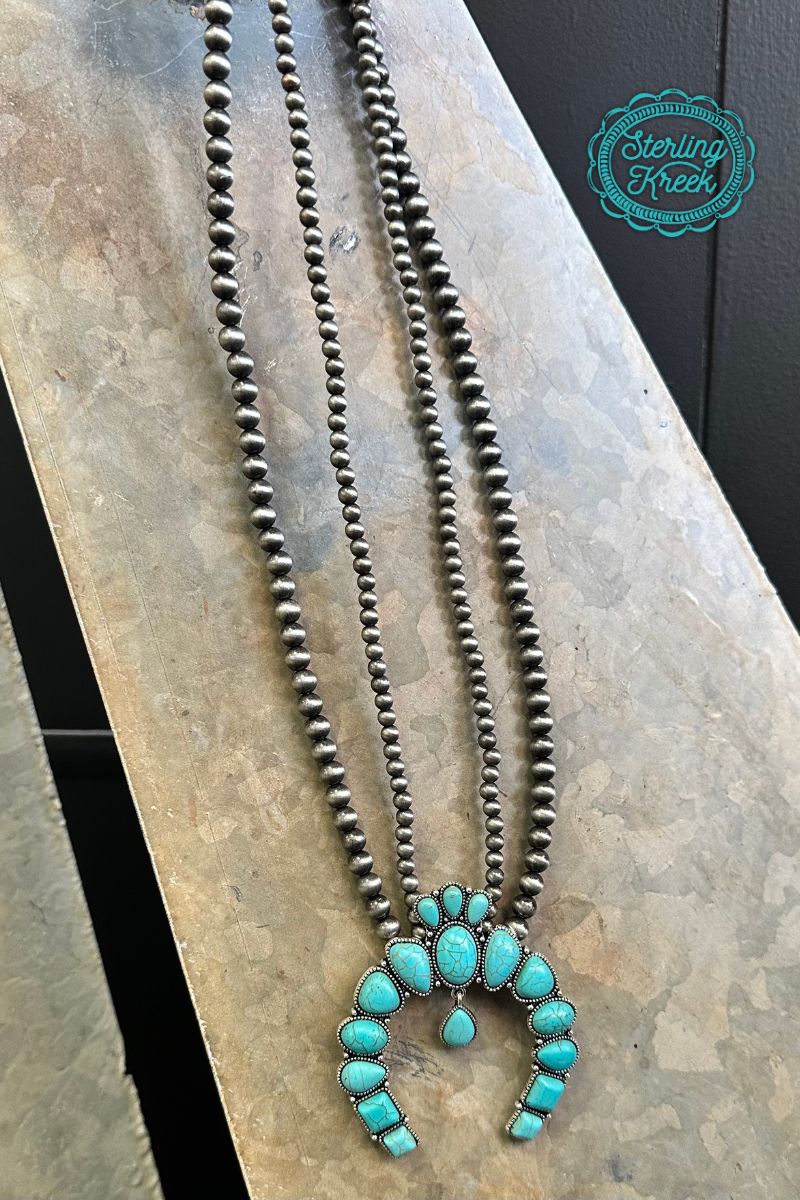 This statement necklace is a winner! Crafted with pearls, it features a lucky horseshoe-shaped squash blossom pendant that's guaranteed to bring you good fortune. Get ready to bring your A-game!