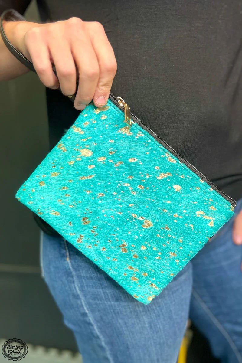 Turn heads with The Penelope Bag! Show off your style with this one-of-a-kind turquoise cow hide bag. Its unique look and solid construction will have you strutting the streets like a true fashionista. Get groovy with this boho-inspired bag!  8" X 6.5"  wristlet strap : 8"
