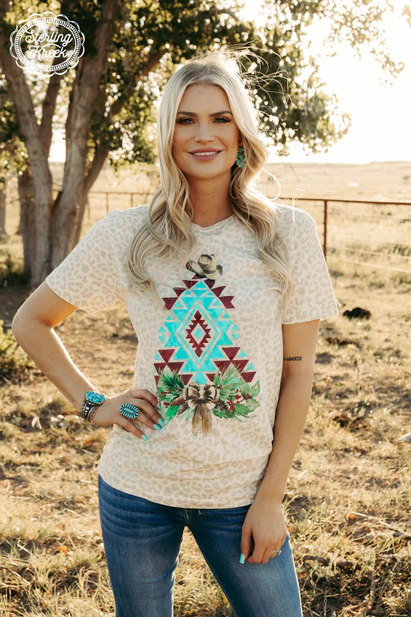 Head in the holidays the western 'n' wild way with our Cowboy Christmas Tee! Boasting an aztec Christmas Tree pattern on a leopard print cream tee topped off with a stylish cowboy hat, it's time to giddy up into the holiday spirit! Yeehaw!