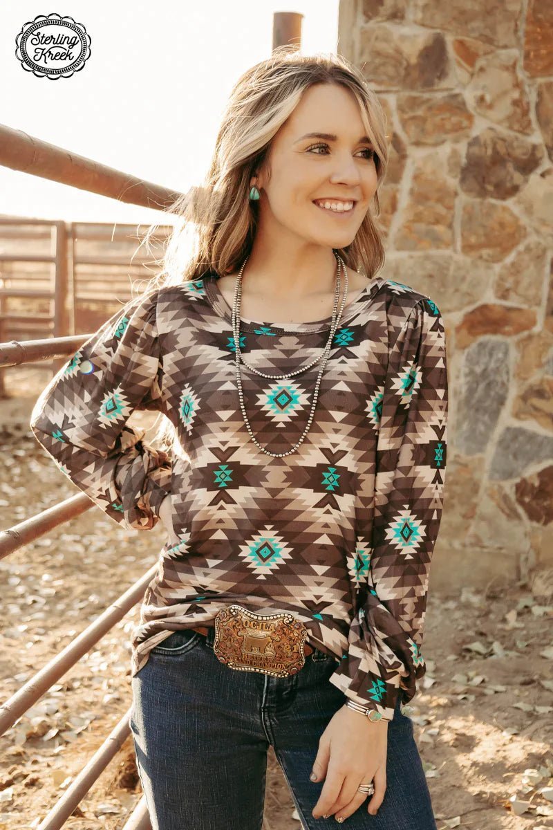 Treat yourself to the DENALI KNIT TOP! This cozy brown long sleeve with a bubble sleeve is the perfect essential for cooler days. With a turquoise and cream Aztec print, its unique style is sure to make a statement. Get ready to turn heads!  100% polyester