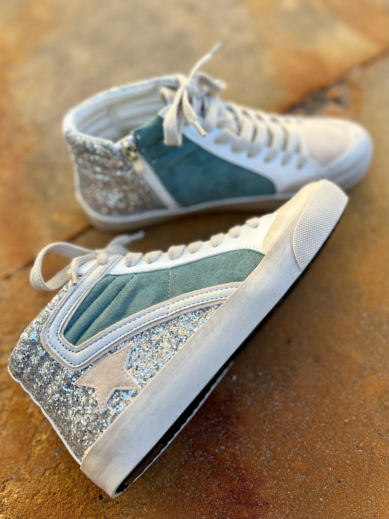 Our Wintergreen Wonderland Sneakers are the perfect blend of luxury and style. These high-tops feature a classic Oxford design in a tan suede-like material, seamlessly embellished with shimmering silver giltter and a green suede like strip on the side.  Slip into these sneakers and take your look to the next level of sophistication.  True to size.   Man made materials 