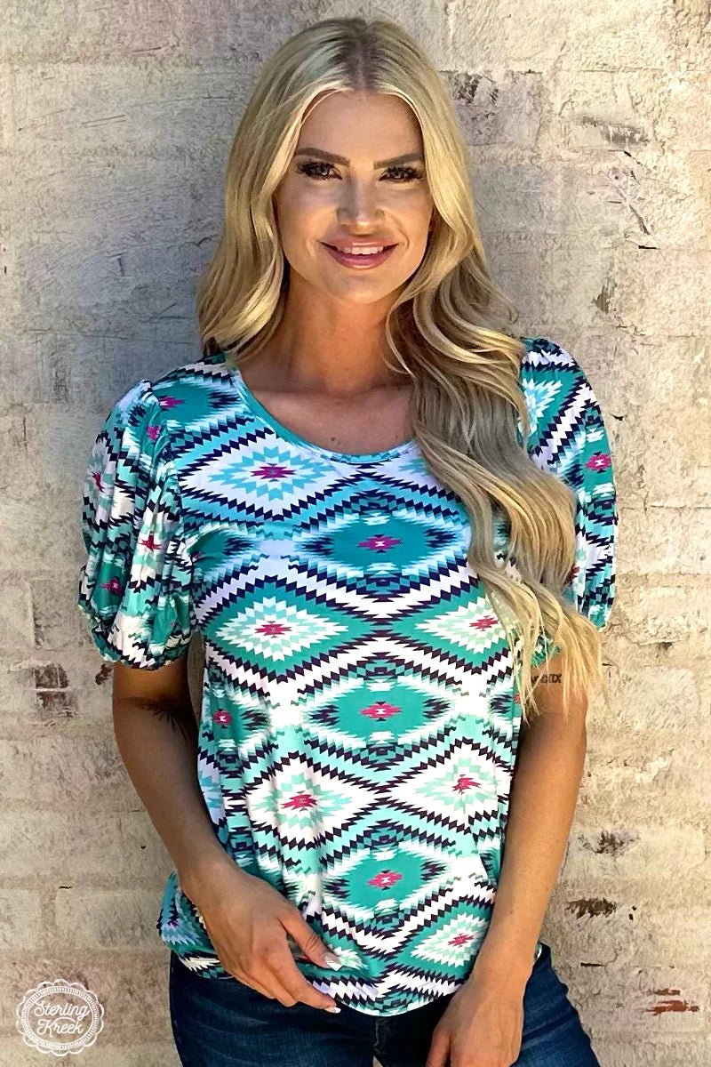 Introducing the Island Vibes Top - a one-of-a-kind statement piece that'll put you at the center of attention! This trend-setting top combines blue and turquoise shades with an eye-catching aztec pattern, finished off with a splash of pink for the perfect pop of color. Ready to look like a work of art? Get your hands on this beauty now!