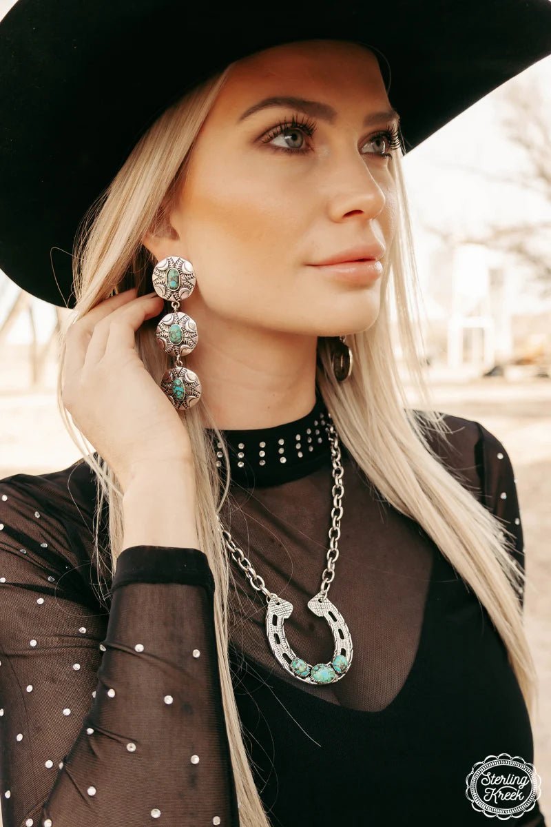 "Add some Southwestern flare to your outfit with our Concho Valley Earrings! These silver dangle conchos feature a stunning turquoise stone that will make a statement wherever you go. Embrace your inner cowgirl (or cowboy) and elevate your style with these unique earrings. Yeehaw!"  length - 3.5"