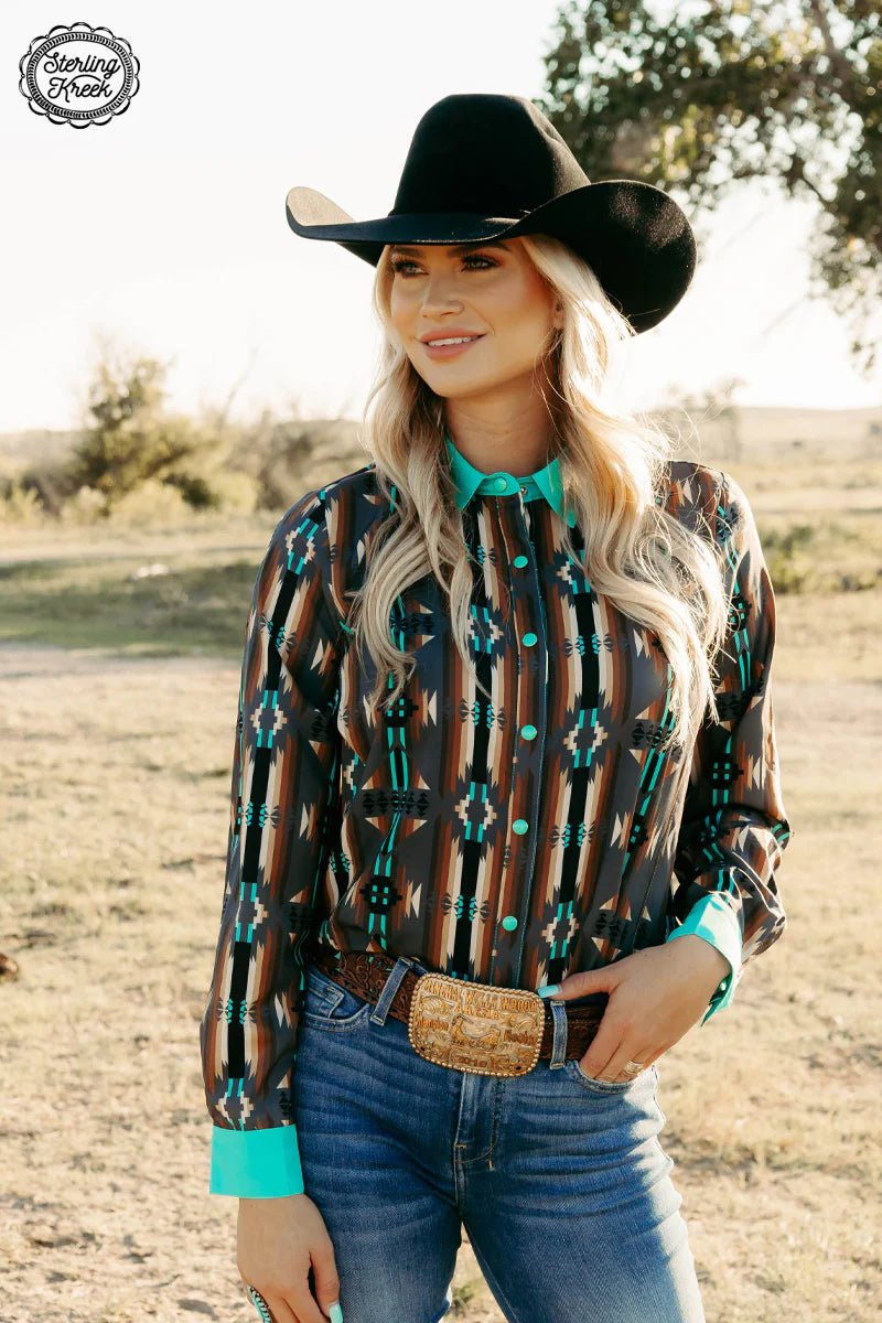 Navigate your way in style with our Red Dirt Road Top! This chic western style shirt has a gray button up, turquoise pearl snaps, and an awesome aztec design with a dash of color from the turquoise collar and cuffs. Lookin' sharp!  95% Polyester 5% spandex