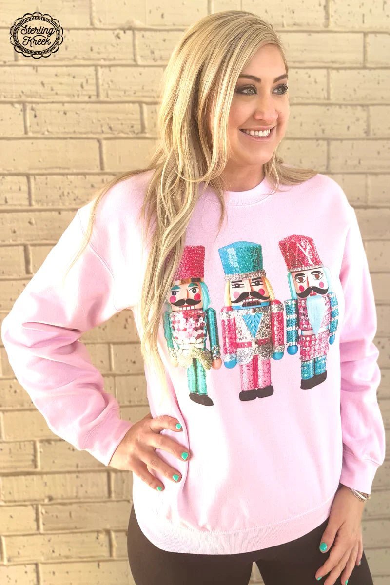 You'll shell out compliments in this adults Let's Get Crackin' sweater! A light pink base forms the perfect backdrop to the three nutcrackers dressed in pink and turquoise sparkly suits. It's the perfect way to crack open a smile from anyone!  50% Cotton 50% Polyester