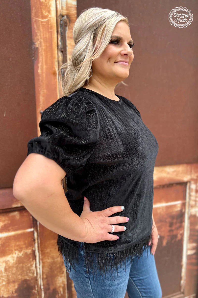 Rise and shine in this sleek and sultry plus size black velvet top! The feathers on the bottom give you that extra flutter and extra oomph to get your day started with style. Make a statement with this fashionable and feisty top that says, "I shine, no matter what!"  82% polyester 12% metalic 6% spandex