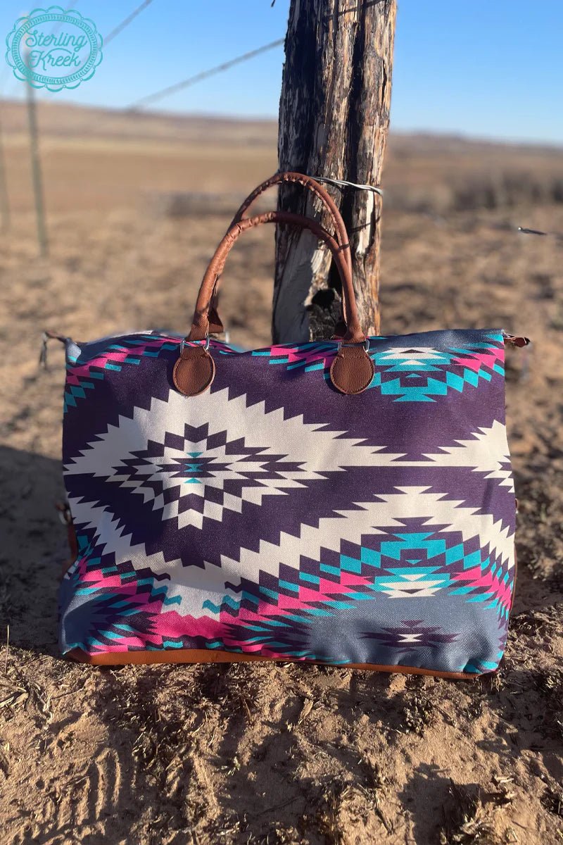 Sterling Kreek Tuscon Cliff XL Tote I Gussied Up Online  Western Style Travel Bag. Women's western accessories. Western Style Bags. Aztec Tote. Western Print. Diamond Aztec Print. Cowboys print travel bag. Purple weekend bag. Pink. White. Purple. Women's western wear. Women's western boutique. Online boutique. Small business. Trendy travel bag. Carry On Bag. Western Boutique. Fast shipping from TX.