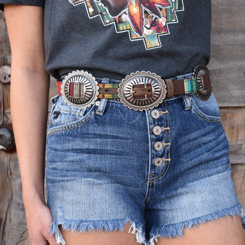 Ariat brown leather backing on serape print belt and silver oval conchos with buckle concho.