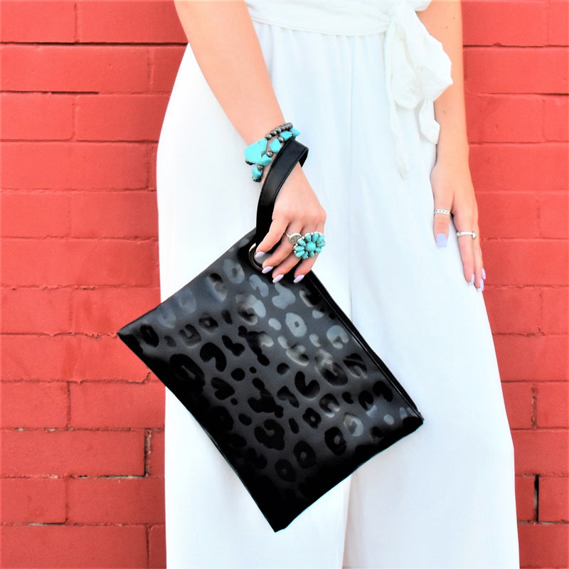 Black tonal shiny vinyl leopard print clutch big enough for any girls weekend! Wristlet strap through a large silver grommet, with zipper closure.
