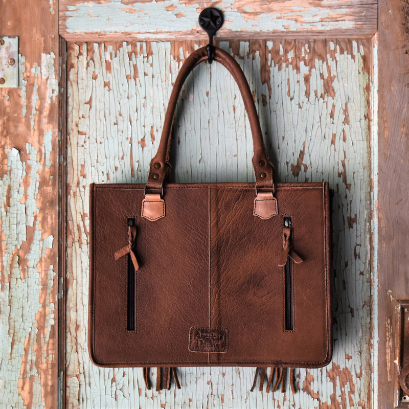 Absolutely beautiful genuine brown spotted hair on hide and brown tooled leather purse! The bag has a large zipper closure pocket, inside zipper pocket, two open pockets. Back is brown leather with concealed carry pocket. Removable tooled crossbody strap.