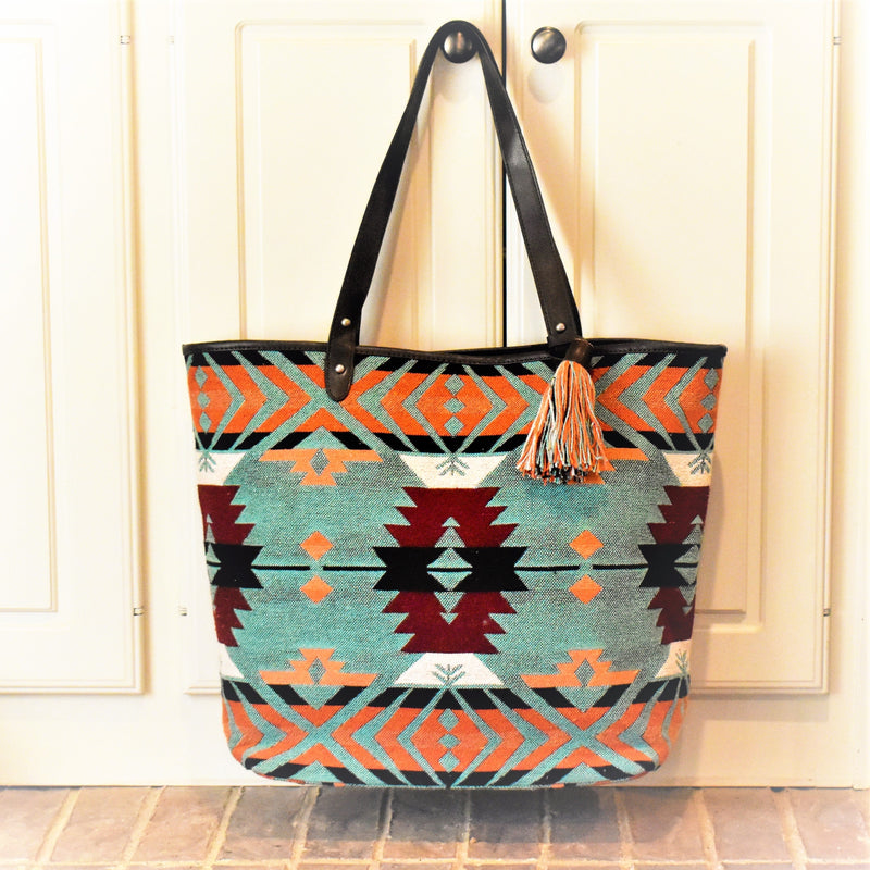 popping coral, mint and maroon toned Aztec print on the woven fabric to the holster included in the back concealed carry pocket. Dark brown leather trim and handles. All finished with a cute decorative tassel! Back zipper pocket.