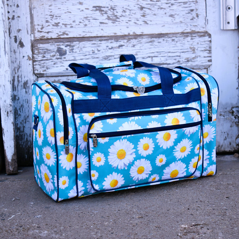 Large sky blue vinyl duffle travel bag with all over white daisy print and navy handles.