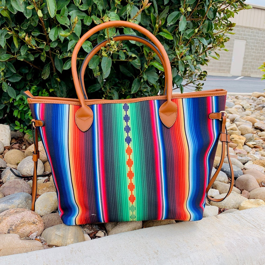 Bright Aztec inspired center strip surrounded by bright vertical serape print. This tote bag comes in a durable fabric canvas with tan vinyl handles and detailing.