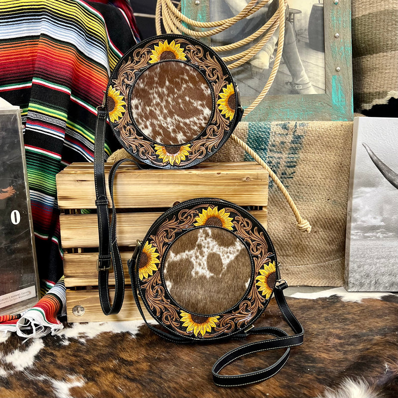 The Canteen In a Blooming Field Bag is a 10" round Hair On Hide with Beautiful Sunflower Tooled Black Leather Accents. The bag features a 3/4 zipper closure and a small zipper closure on the back. The bag features 2 different cowhide variants.    10" round in size and 2" Wide.   48" adjustable strap 