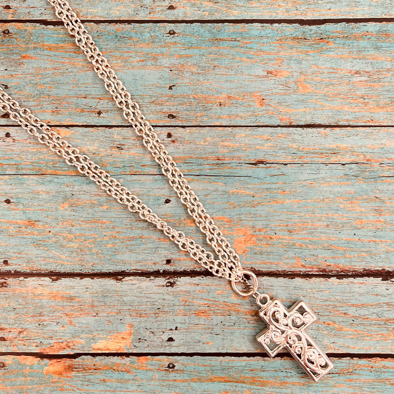 The At The Door of the Cross Necklace is a 18" Double Strand Silver Chains Necklace with a silver hollow scroll design Cross as the Pendant. It has a 3" adjuster clasp. This necklace is super classy!  *matching earrings included*
