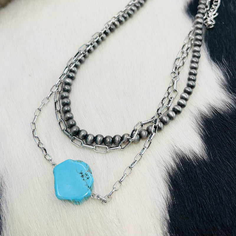 The Tack and Bridle Necklace is a 3 strand western necklace with a Turquoise Nugget Pendant. There is a 12" Navjao Pearl strand,  a 14" silver chain link strand, and a 16" silver chain with a Turquoise Nugget Pendant. It also has a 3" adjuster clasp.
