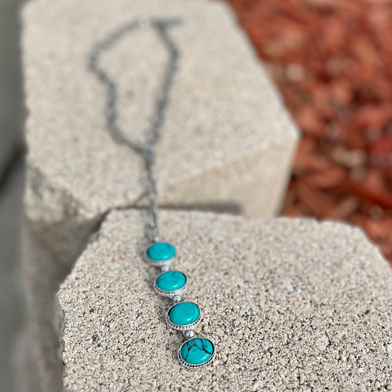 The Southern Iron Necklace is a 14" Silver Chain with a 3" Adjuster clasp. The necklace features a 5 1/2" drop with a 4 turquoise stone dangle. The Necklace is very classy and will add tons of character to any outfit. 