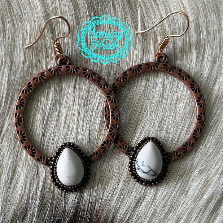 The Eye Of The Beholder Earrings are a stamped copper hoop with 1 tear drop white stone  at the bottom.   The hoop is 1" in total diameter and on a fish hook back.