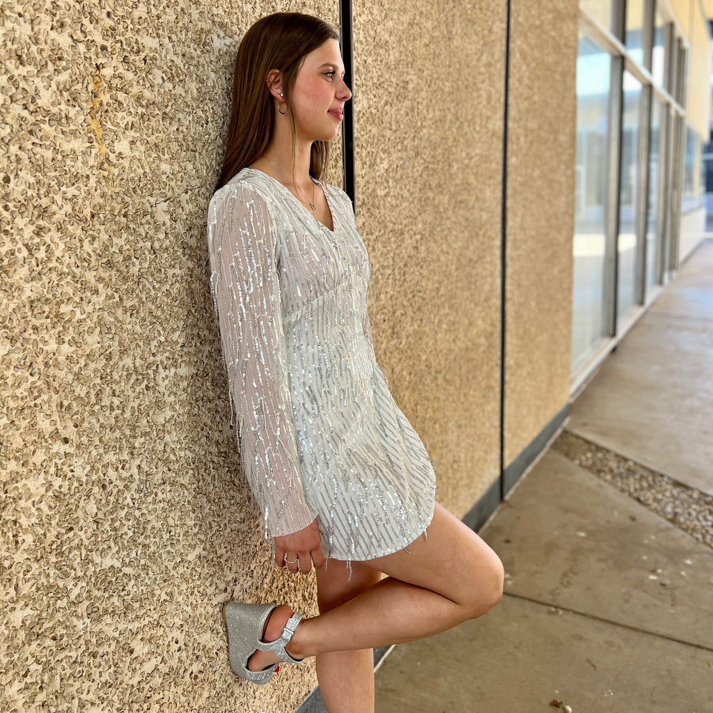 Look glamorous in our Time Square Party Dress. Crafted with a vneck and finished with shimmering silver sequins, this long sleeve mini dress is just what you need for that special event. Tassel details make this white party dress a stand-out while still ensuring you turn heads and look amazing.