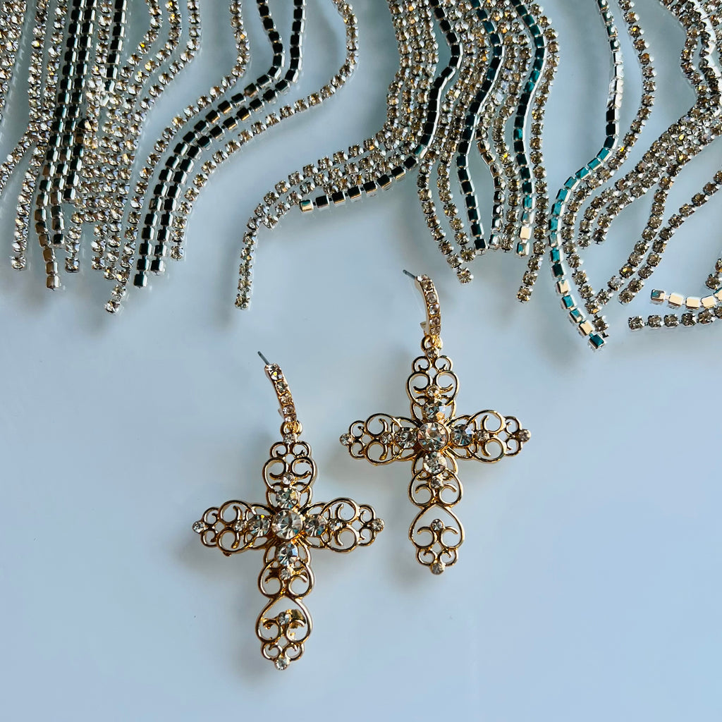 These Golden Cross Earrings feature a classic scroll design inlaid with small rhinestones. Crafted from durable gold, they measure 2 1/2" and hang elegantly in any setting. A timeless choice of jewelry.