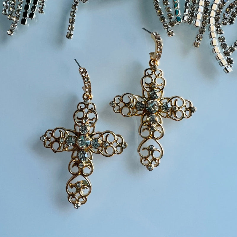 These Golden Cross Earrings feature a classic scroll design inlaid with small rhinestones. Crafted from durable gold, they measure 2 1/2" and hang elegantly in any setting. A timeless choice of jewelry.