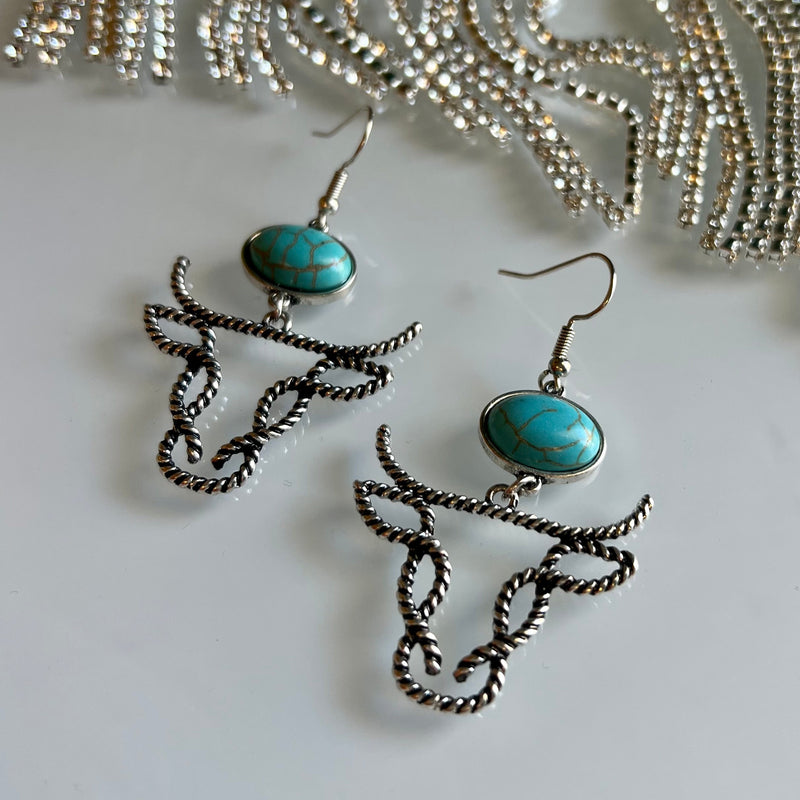 Barb Wired Bill Earrings offer a western-style twist to your everyday look. Featuring a high polish finish, twisted cable wire featuring a cow head flame set with an oval turquoise gemstone, you'll make a statement with these fish hook dangle earrings.