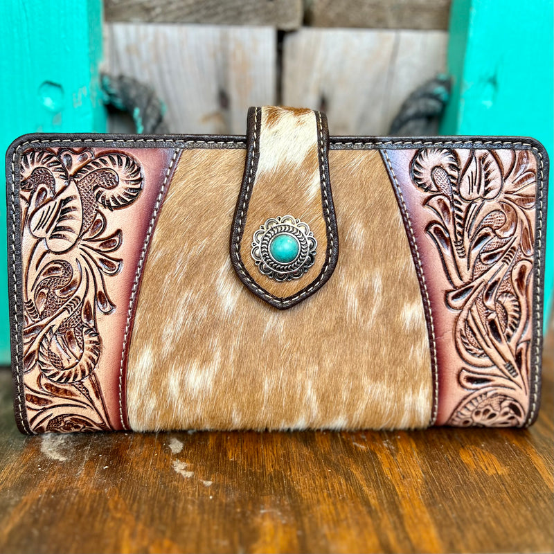 Head out in style with the Roscoe Ridge Hand Tooled Wallet! This luxurious brown leather wallet features a one-of-a-kind floral tooling, cow hide accents, and a sparkling silver flower concho with turquoise stone. You'll be looking fly with the secure fold-over flap closure to keep all your stuff safe. Now that's what I call wallet worthy!  Dimensions: 8" W X 4"H