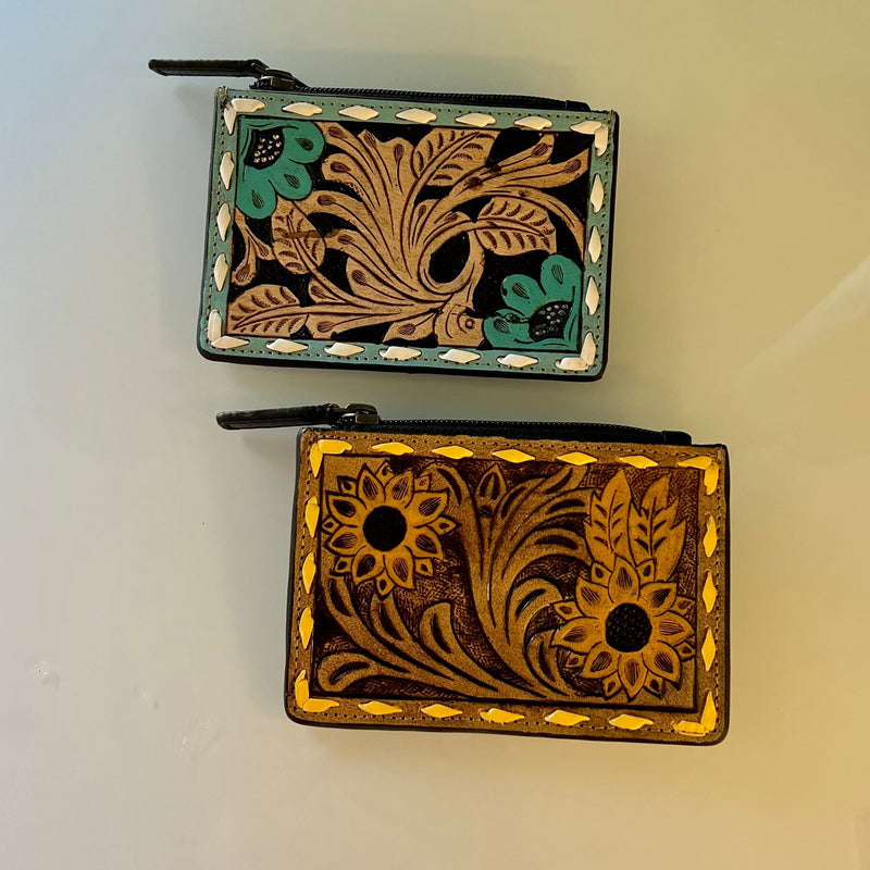 These Beautiful Tooled Leather Credit Card Holders are perfect for a handheld option. They are the perfect size to slip in your back pocket for a shopping day. Feature a zipper pouch for safe keeping, and four card slots. They are Gorgeous Tooled Leather with 2 different variants offered.   Dimensions: 5" X 3"