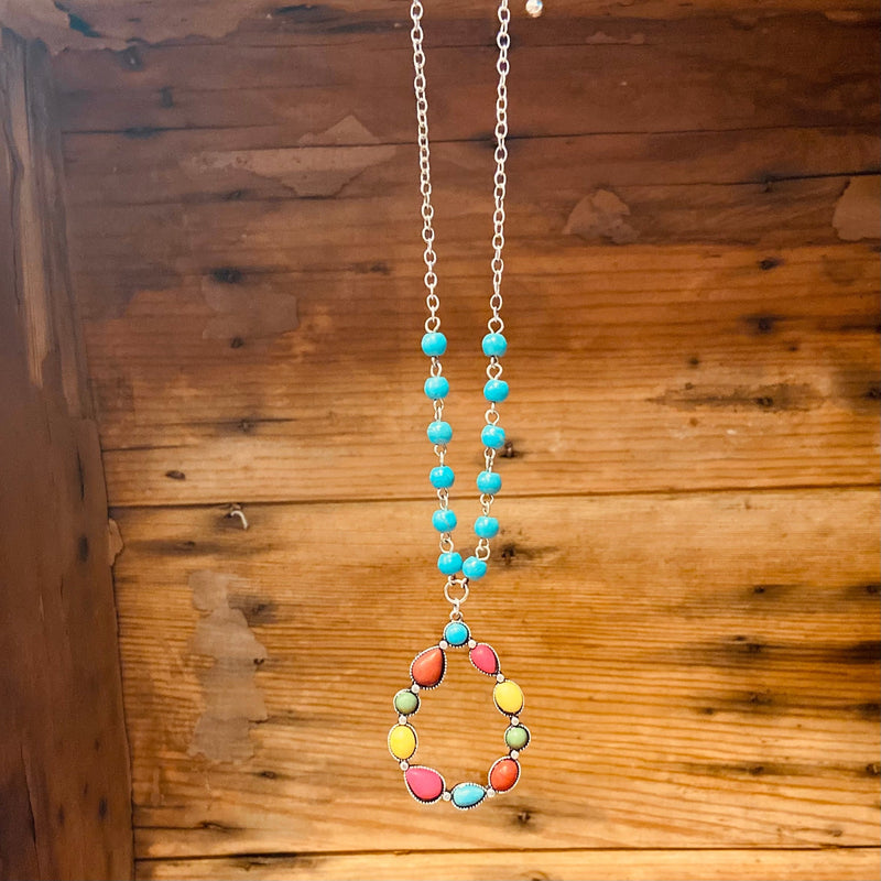This Color Me All Over Tear Drop Necklace showcases a western pendant formed with shaped stones in a charming tear drop design, all in a graceful multi color hue tones.  The silver 20" adjustable chain with turquoise tone beads are sure to be a go-to piece for everyday elegance.