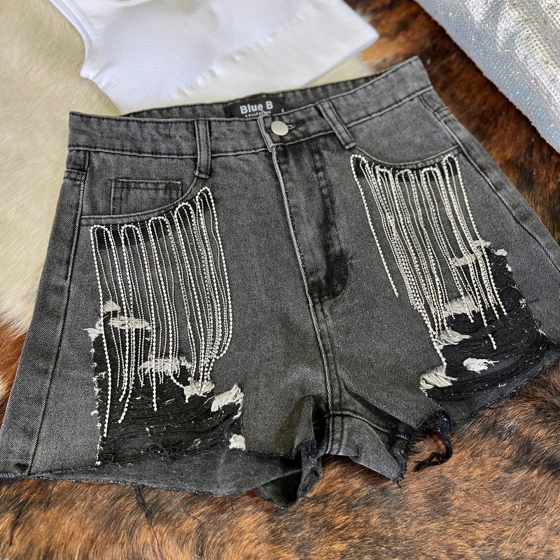 These short are made to be seen and heard! Whether you fancy Coachella or SXSW, you need these bad boys! Black denim high waisted shorts with ripped frayed hem and rhinestone fringe detail around the front pockets.  Rise: 12"  Inseam: 4"  90% Cotton, 10% Polyester