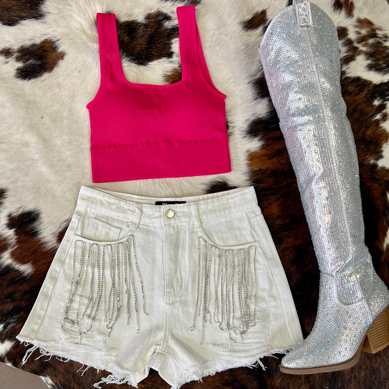 These short are made to be seen and heard! Whether you fancy Coachella or SXSW, you need these bad boys! White denim high waisted shorts with ripped frayed hem and rhinestone fringe detail around the front pockets.  Rise: 12"  Inseam: 4"  90% Cotton, 10% Polyester