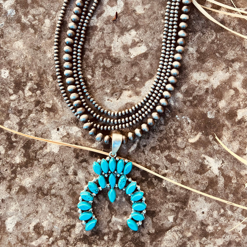 The Turquoise In The Wild Necklace is a 18" long, tiny navajo pearl & squash blossom natural turquoise pendant necklace. The stones very in size, color, and shape. The 4 strand necklace is a 18" necklace with a 5" extender. The Pendant is 2 1/2" long.