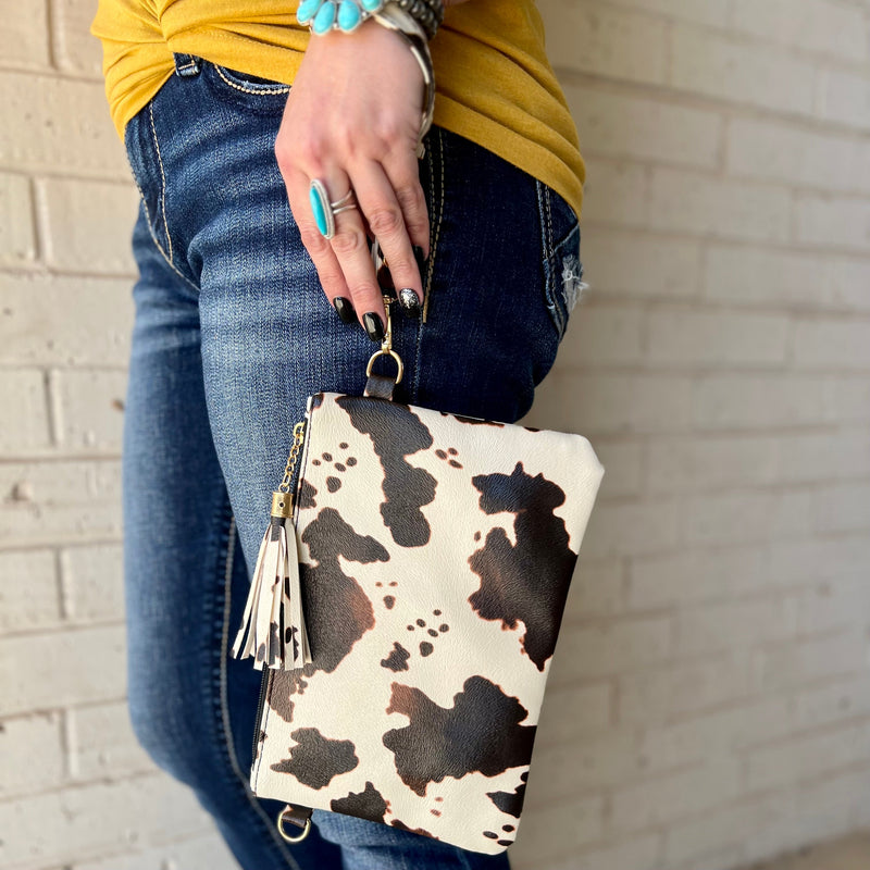 The Arlington Cow Wristlet is the perfect size clutch for everyday use. Featuring a full zipper closure, lined inside, and fringe tassel accent. This wristlet measures 10" X 7".