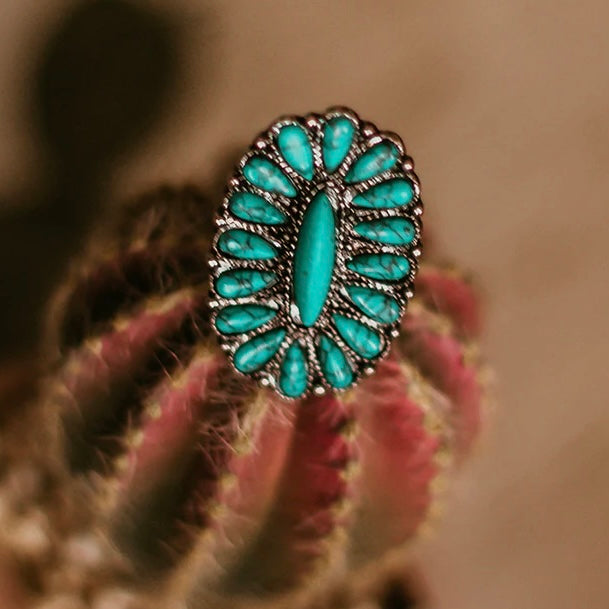 The Pecos Adjustable Ring is a Beautiful small 16 turquoise stone tear drop cluster surrounding 1 larger oval turquoise stone. It was a adjustable band that can be sized to it anyone. It is the perfect size and so BEAUTIFUL!! The total size of the cluster is 1 1/2" in length by 1" in width.