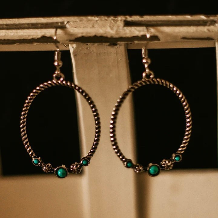 The Hold The Reign Earrings are a simple twisted silver hoop with 3 turquoise stones and 2 star stamped designs attached at the bottom.  The hoop is 2" in total diameter and on a fish hook back.
