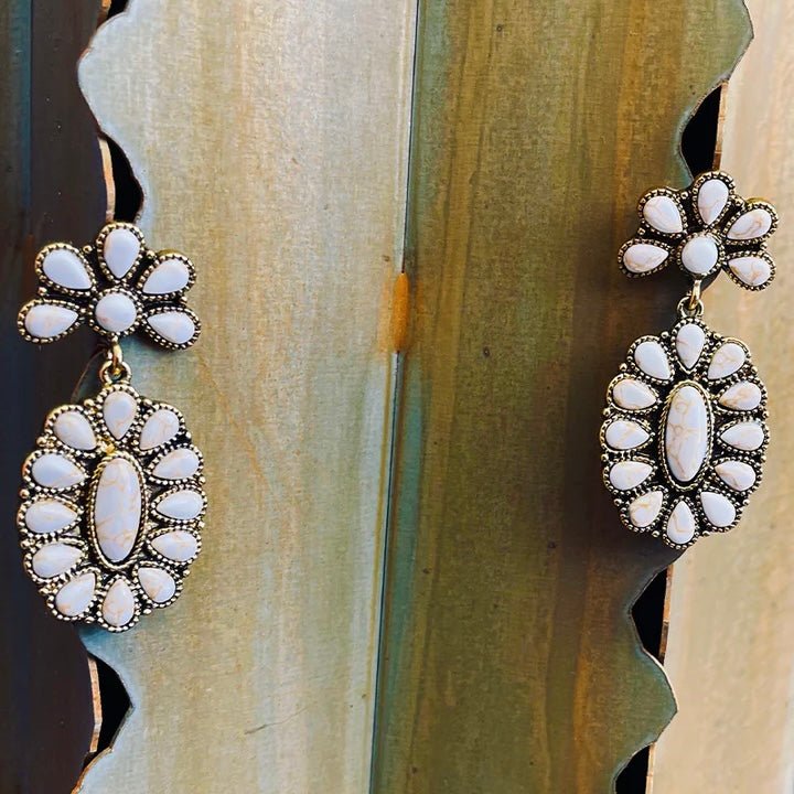 The Gilded Peak Earrings are a 1 1/4" white stone squash blossom attached to 6 stone fanned white stone design on a post back. The earrings are 2" in total length.