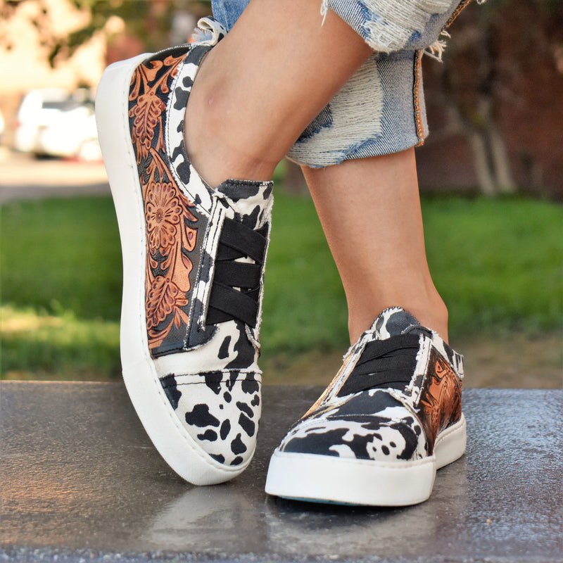Give your feet some style with these classic black and white cow print & tooled leather flat sneakers. They'll be your go-to pick for casual office days, shopping, or dress them up for a night on the town. 
