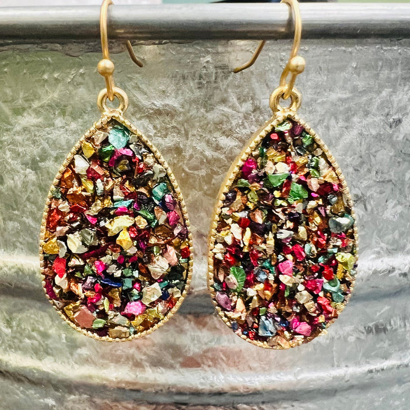 The Bayler Grace Teardrop Earrings are a show stopper. The earrings come in 4 different colors. They are 1 1/4" teardrop with multiple rock gem stones. They are inlayed in a gold tear drop background. They are on a fish hook back.