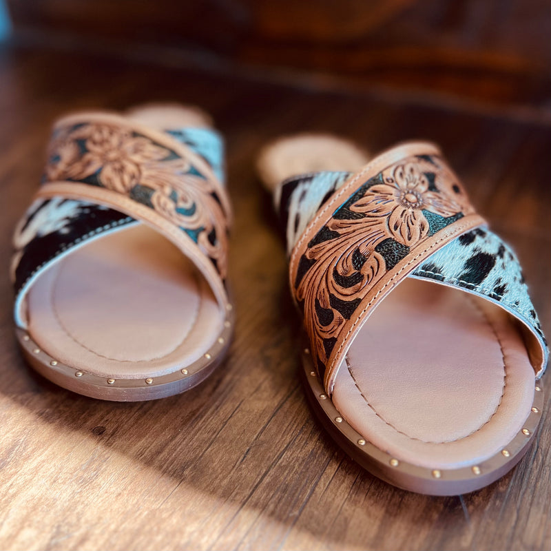 By Myra  Criss-cross strap slide on sandals in hand tooled leather and black and white hair on hide.   Rubber sole and cushioned foot bed.   True to size, if between sizes, size down 