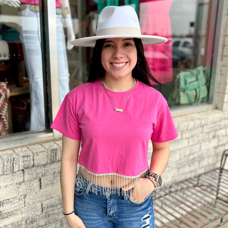 This stylish pink crop top is crafted from soft cotton fabric and designed with an eye-catching rhinestone fringe for maximum sparkle. The short sleeve design is perfect for hot summer days and adds a touch of glamour.  Material: 95% Cotton, 5% Elastane