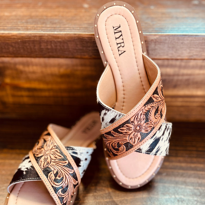 By Myra  Criss-cross strap slide on sandals in hand tooled leather and black and white hair on hide.   Rubber sole and cushioned foot bed.   True to size, if between sizes, size down 