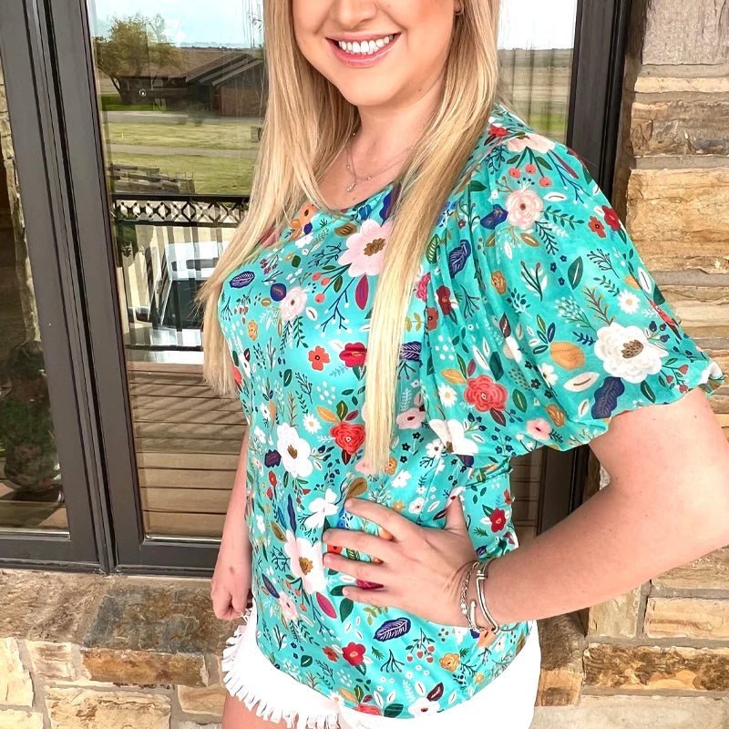 Flaunt your fashion finesse with the Beautiful in Bloom Top! Featuring a floral turquoise design on a solid body with delicate mesh bubble sleeves, you're guaranteed to add a carefree and stylish look to your wardrobe. It's perfect for rocking your best look — you'll be confident and looking sassy!  Meredith is wearing a Medium  50% POLYESTER 45% COTTON 5% SPANDEX