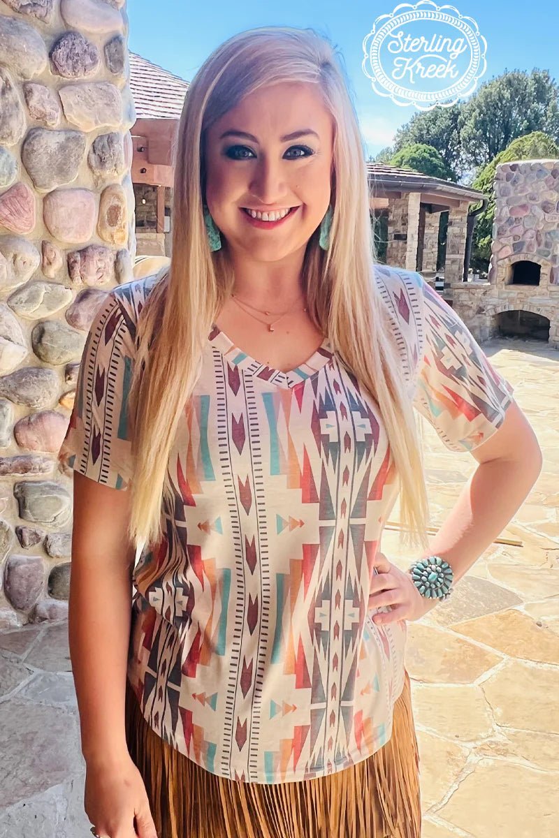 Take a step out of your comfort zone and into the wild with our BY YOUR GRACE TOP! This aztec-inspired vneck top will keep you looking fierce; from its distinctive pattern to the flattering cut, you'll look your best with every wear. Get ready to make a statement and step out in style!  Meredith is wearing a Medium  55% cotton 40% polyester 5% spandex   Measurements are with shirt laid flat 