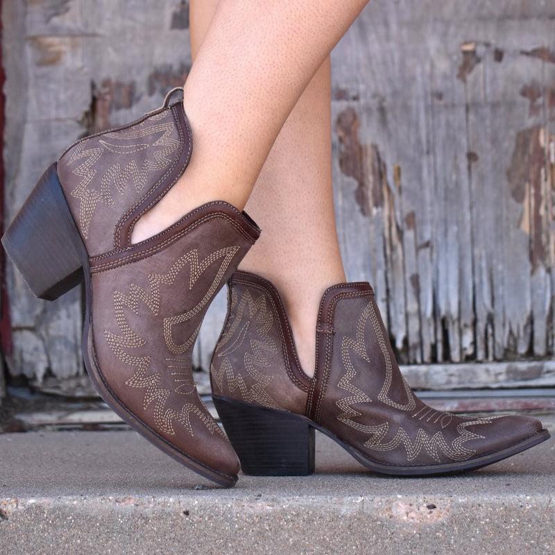 By Myra  Genuine brown leather notched ankle booties with decorative contrast stitching in tan. Pointed toe.