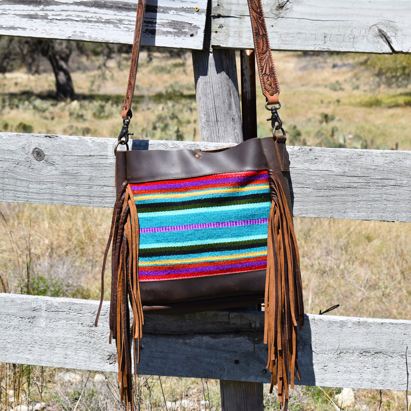 Satchel bag Aztec saddle blanket front and sanded brown leather surround and back. Includes removable tooled leather crossbody/shoulder strap and center lobster claw closure top. Brown side fringe and unlined interior.