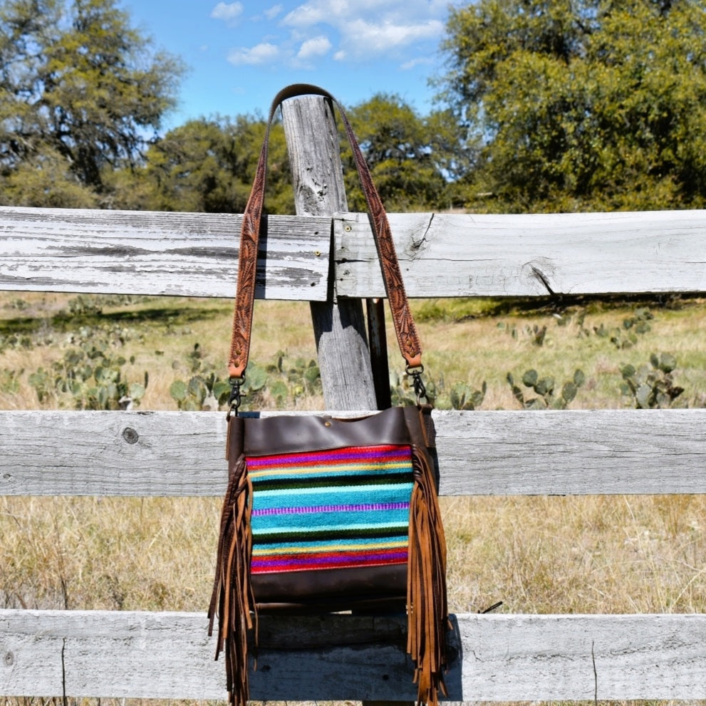 Satchel bag Aztec saddle blanket front and sanded brown leather surround and back. Includes removable tooled leather crossbody/shoulder strap and center lobster claw closure top. Brown side fringe and unlined interior.