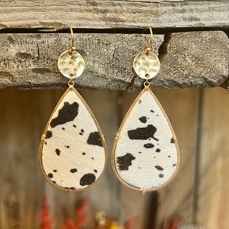 These Spotted Perfection Earrings come in 2 different colors. They are a black and white cow print cowhide and a brown and white cow print cowhide. They are a tear drop design attached to a small gold hammered circle on a fish hook.