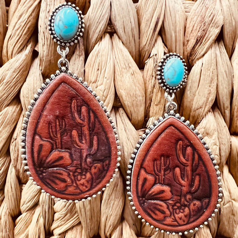 These Leather Stamped Earrings have 3 different designs. The tooled leather design are on a 2" tear drop background. They are attached to a single turquoise stone on a post back.