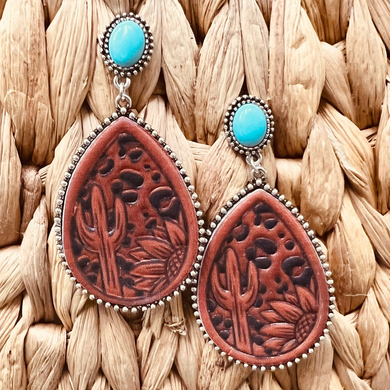 These Leather Stamped Earrings have 3 different designs. The tooled leather design are on a 2" tear drop background. They are attached to a single turquoise stone on a post back.